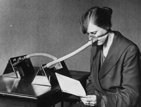 a woman uses an air purifying apparatus thought to make breathing safer in 1919.